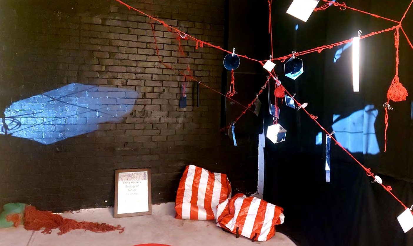 Red yarn, hanging mirrors and striped bags in a dark room with a projection