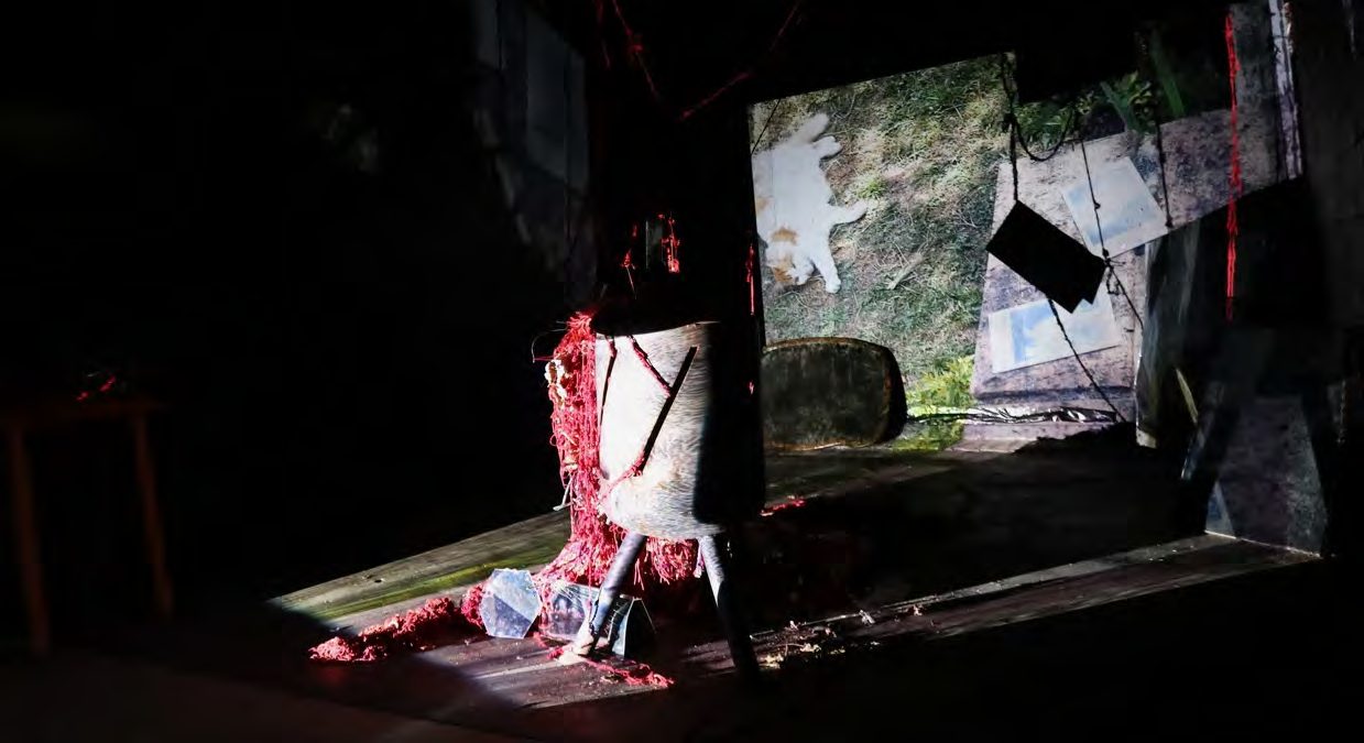 A chair wrapped in yarn and a projected image in a dark gallery
