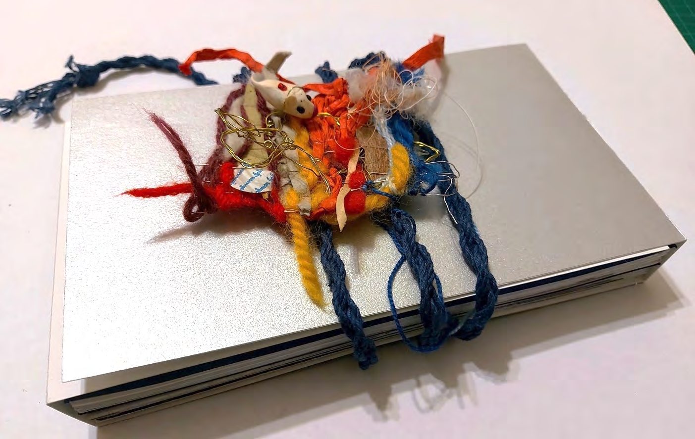 A small tangle of red and coloured yarn resting on a closed laptop