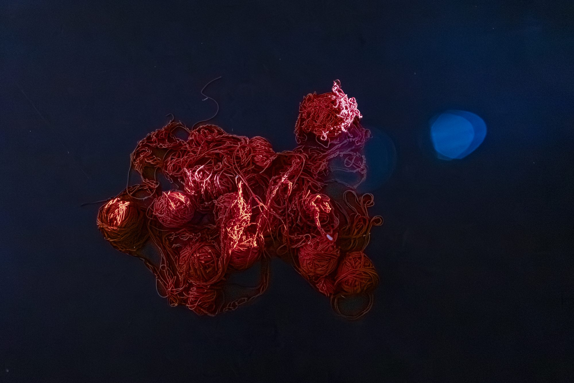 A tangle of red yarn on a dark surface