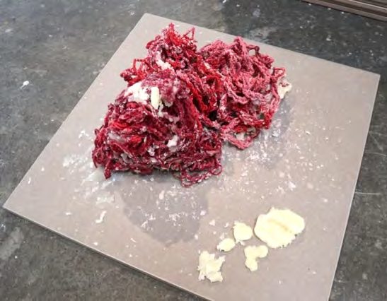Wax-coated red yarn piled on a ceramic tile