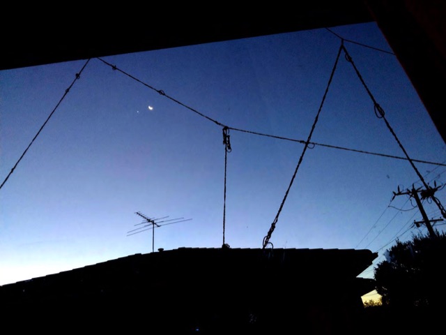 Red yarn lines strung against a darkening sky above rooftops