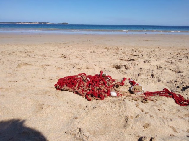 A mass of red hemp yarn lying on a sandy beach