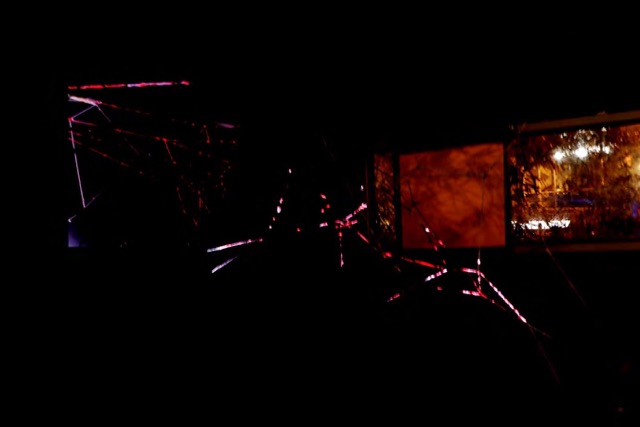 Red yarn lines lit in a dark space with projected light